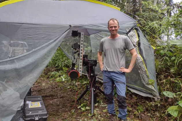 Mikkel Brydegaard står framför ett tält med mätutrustning i en tropisk skog. Foto